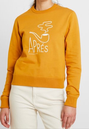 Mosterdgele sweatshirt met een ronde hals, voorzien van een witte bies en de tekst "APRÉS". Zacht materiaal met ribgebreide mouwen en zoom.