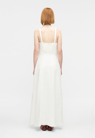 Μακρύ φόρεμα από λευκό λινό με ρυθμιζόμενες τιράντες, εφαρμοστό μπούστο και φαρδιά φούστα. Διαθέτει υφασμάτινη φάσα με υφή στην πλάτη.