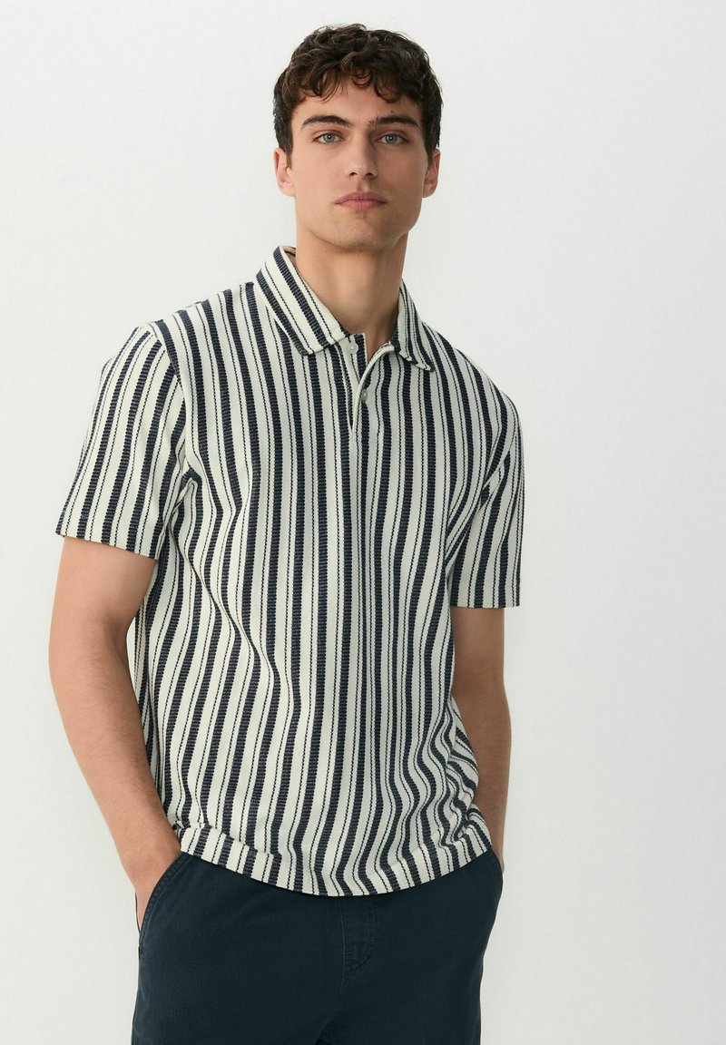 Polo de manga corta, con un patrón de rayas verticales en azul marino y blanco. Material de algodón con un cuello clásico y un ajuste relajado.