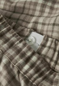 Bruin en wit geblokt stof met een zachte textuur; voorzien van een elastische tailleband met een wit label en een knoopsluiting.