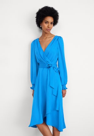 Blue wrap dress with long sleeves, A-line shape, and a tie waist. Features a deep V-neck and soft, smooth fabric with a flowing hem.