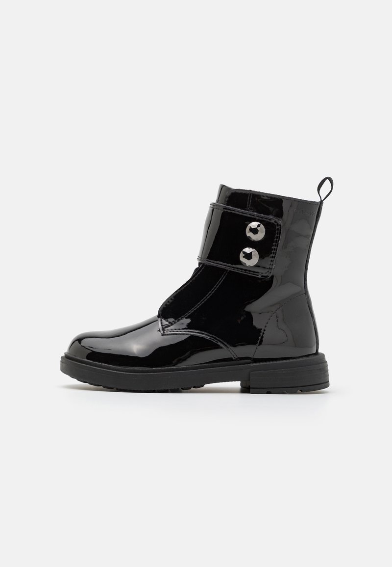 Black patent leather ankle boot with decorative buttons, round toe, and a textured rubber sole. Features a pull loop for easy wear.