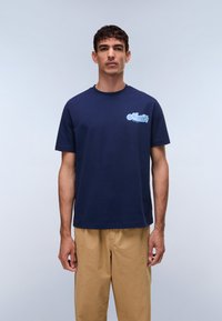 Μπλε ναυτική βαμβακερή μπλούζα με κοντά μανίκια και στρογγυλή λαιμόκοψη. Διαθέτει ανοιχτό μπλε γραφικό σχέδιο στην αριστερή περιοχή του στήθους. Σχεδίαση με άνετη εφαρμογή.