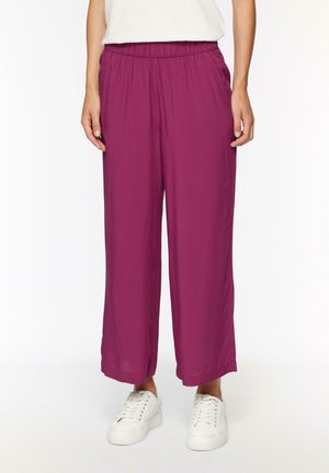 Paarse wijde pijpen met een lichte stof en een elastische tailleband. Gecombineerd met witte sneakers, wat een casual look creëert.