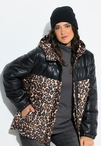 Giacca a vento nera in pelle con stampa leopardata, dotata di cappuccio, con design trapuntato, polsini elasticizzati e un dolcevita grigio sotto.