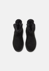 Stivaletti neri alla caviglia in suede con fodera morbida e soffice e punta rotonda. Presentano una suola in gomma e un design semplice e pulito.