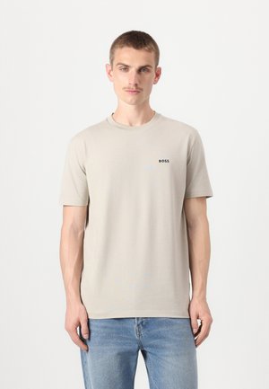 Tricou bej cu mânecă scurtă, cu guler rotund, având un mic logo negru "BOSS" în zona stângă a pieptului. Textură netedă, croială lejeră.
