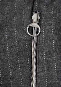 Tissu gris à fermeture éclair avec des rayures verticales. Il présente un tirette de fermeture éclair en argent et des dents métalliques, avec un tissage texturé et une finition douce.