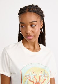 Crèmegekleurde katoenen t-shirt met korte mouwen, voorzien van een cirkelvormige "Endless Summer" grafiek met palmbomen en een zonontwerp.