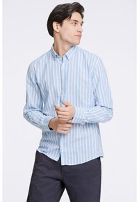 Camisa de rayas azul claro y blanca con cuello abotonado, mangas largas y un ajuste relajado. Fabricada con tela ligera.