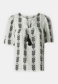 Blusa blanca con estampado de hojas negras, mangas cortas abullonadas, escote atado con borlas y detalles fruncidos en el busto.
