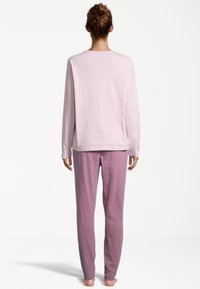 Long-sleeve, light pink top and matching lavender pants made of soft fabric, designed for comfort with a simple, relaxed fit.