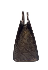 Borsa lucida marrone scuro con grandi lettere monogrammate in rilievo e due manici verticali, vista di lato.