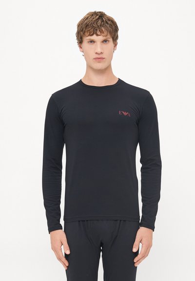Chemise noire à manches longues en tissu lisse, dotée d'un col rond et d'un petit logo rouge sur la poitrine gauche.