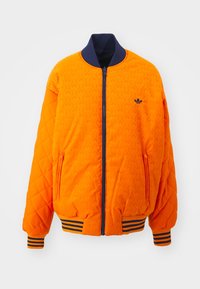 Orange quilted bomber jacket with navy ribbed collar and cuffs. Features zip closure and side pockets. Accented with emblem on chest.