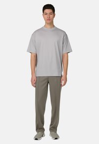 T-shirt à manches courtes gris clair avec un col rond, associé à un pantalon vert olive. La tenue présente une coupe décontractée et une texture douce.