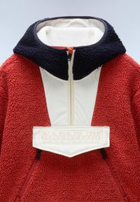 Rød fleece pullover med en hvid panel og navy krave. Har en frontlynlås, logo patch og sidelommer med lynlås for ekstra funktionalitet.