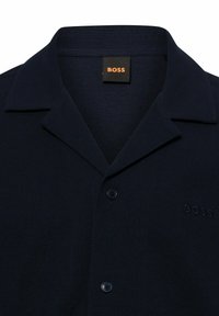Donkerblauw gestructureerd herenoverhemd met spread collar, twee blauwe knopen en klein geborduurd "BOSS" logo op de borst.