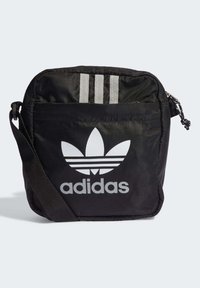Borsa a tracolla nera Adidas con logo Trefoil bianco, tre strisce verticali, tasca con zip frontale e tracolla regolabile.
