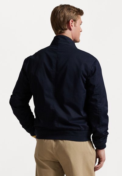 Marineblaues Bomberjacke mit Stehkragen, gerippten Bündchen und Saum. Hergestellt aus glattem Stoff mit einem klaren, minimalistischen Rückendesign.