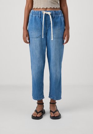 Lysblå, løstsiddende denim joggers med elastisk talje og hvid snor. Har to forlommer og cropped kant.