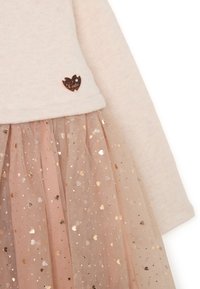 Hellbeige Oberteil mit einem roségoldenen Herzakzent; geschichteter Tüllrock in sanftem Pink mit metallischen goldenen Herzen und Punktemustern.