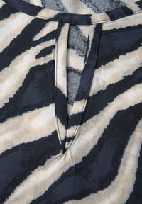 Zebra print fabric with black and beige colors, featuring a notch at the neckline and a soft, textured surface.