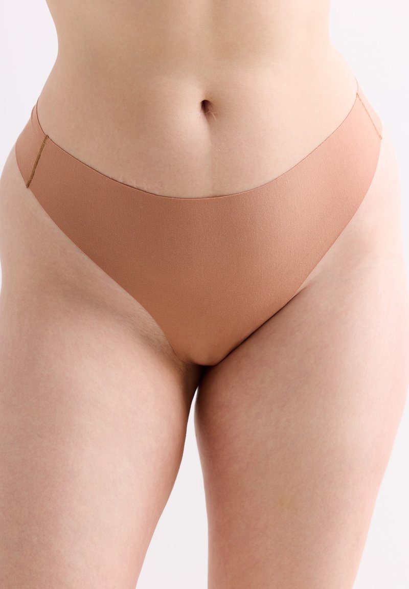 String léger marron, en tissu lisse avec une taille basse. Le design est minimaliste, sans coutures ni motifs visibles.