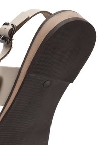 Sandal in pelle naturale con una cintura marrone e una suola in gomma nera texturizzata. Caratterizzato da una soletta con motivo legno e una fibbia in metallo argentato.
