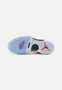 Nike Air Jordans avec une semelle extérieure en caoutchouc bleu translucide, une semelle intermédiaire blanche et un logo Jumpman rouge, avec un motif de traction en chevrons.