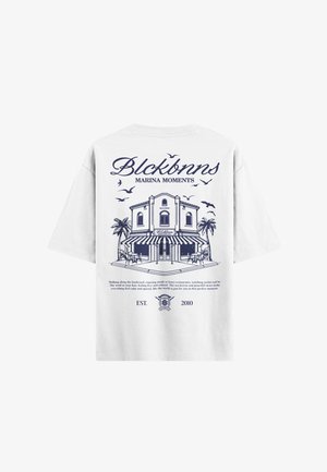 Weißes Baumwoll-T-Shirt mit einem blauen Grafikmotiv eines Gebäudes, umgeben von Palmen und Vögeln, und dem Text "Blckbnns Marina Moments" darüber und darunter.