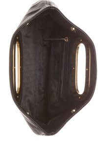 Intérieur de sac à main en cuir noir avec doublure en tissu à motifs, poche zippée et découpes ovales dorées sur les deux poignées.