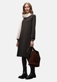 Tummanruskea pitkähihaisen mekon seurana on vaalea huivi. Mallilla on ruskea mokkanahkainen laukku ja mustat nilkkurit. Kaiken kaikkiaan sileäpintainen.