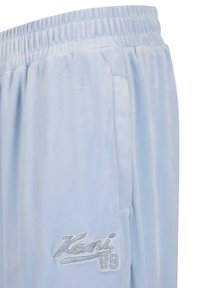 Joggers in velluto azzurro chiaro con vita elastica, tasche laterali e logo ricamato con "Kani 89" in bianco. Texture liscia e morbida.