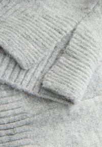 Šedá vlněná látka s žebrovanou texturou, obsahující se překrývající vrstvy. Měkká a huňatá textura s různými odstíny šedé po celé ploše.
