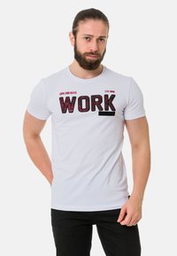 Weißes Baumwoll-T-Shirt mit einem auffälligen schwarzen und roten "WORK"-Grafikdruck, kurzen Ärmeln und einem klassischen Rundhalsausschnitt.