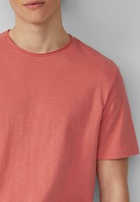Korte mouwen, ronde hals t-shirt in een zachte koraalkleur met een subtiele textuur en een gladde stofafwerking.