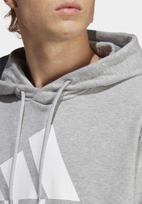 Felpa grigia in misto cotone, con un grande logo bianco, con coulisse e una finitura morbida e testurizzata.