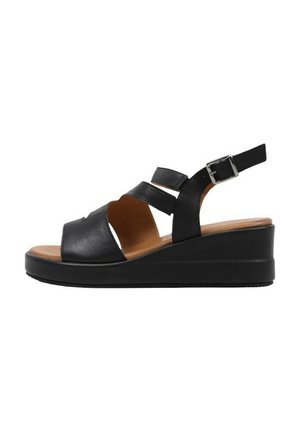 Sandalias de cuña de cuero negro con dos tiras frontales, correa ajustable en el tobillo y suela de goma texturizada. Plantilla marrón visible.