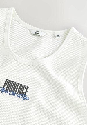 Witte mouwloze tanktop van ribbad, met zwarte en blauwe "PROVENCE" tekst op de voorkant. Etiket toont maat medium.