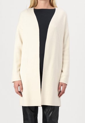 Gilet crème à ouverture frontale, à manches longues et à coupe décontractée, fabriqué en tissu doux avec une texture lisse.