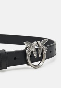 Black leather belt with a round silver buckle featuring two detailed birds facing each other, textured wings, and a smooth finish.