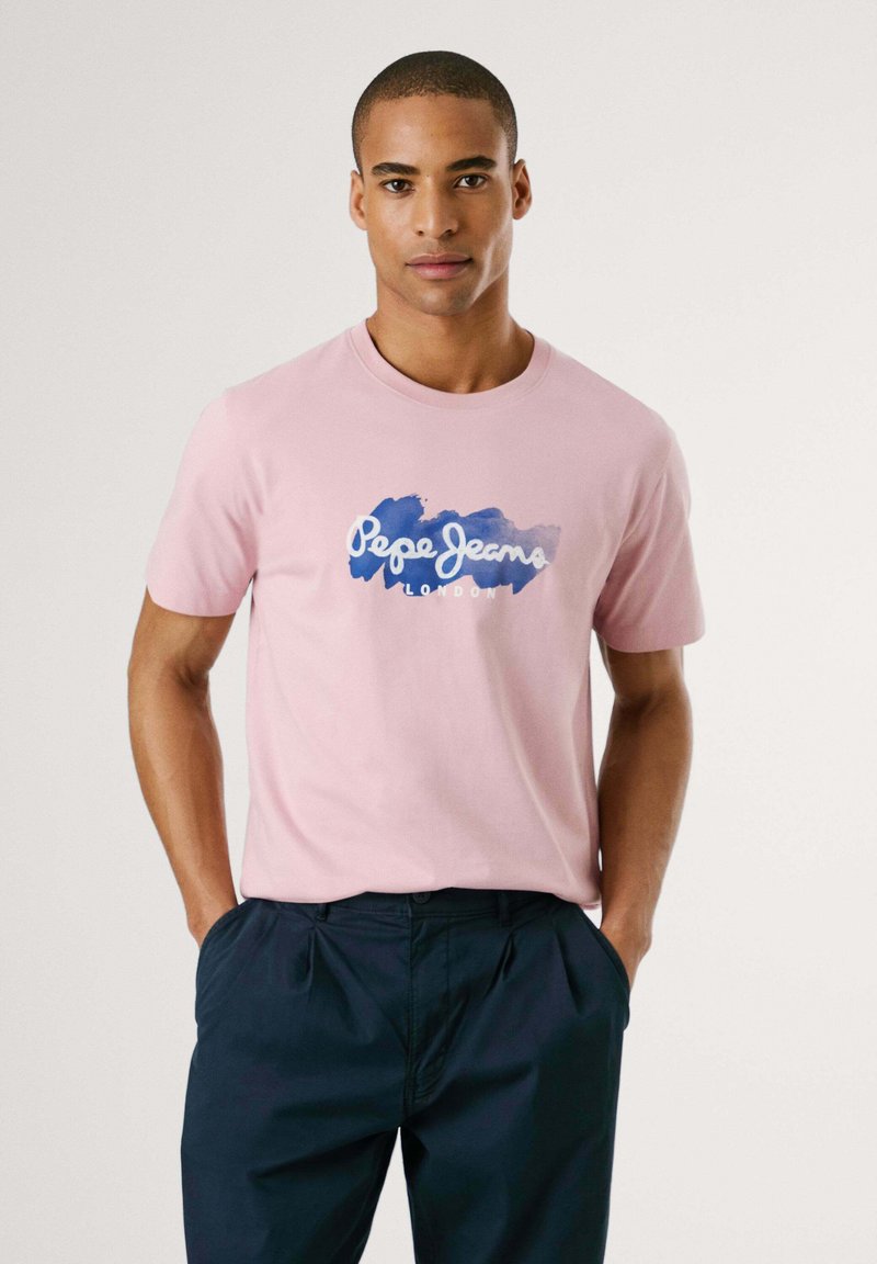 Světle růžové bavlněné tričko s kulatým výstřihem, na přední straně s modro-bílým grafickým potiskem "Pepe Jeans LONDON". Nosené s námořnickými kalhotami.