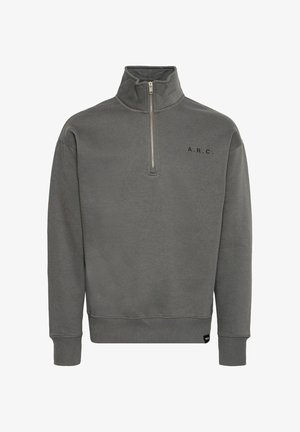 Pelēka augsto apkakli ar rāvējslēdzēju, pirmajā rāvējslēdzēja pusē, ar ribotām piedurknēm un melnu tekstu "A.R.C." uz krūtīm. Mīksta auduma tekstūra.