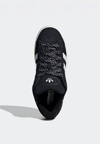 Crne suede tenisice s teksturiranim crno-bijelim vezicama, bijelim prugama sa strane i okruglim logotipom na jeziku.