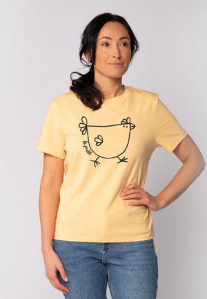 Gelbes Baumwoll-T-Shirt mit einem schwarzen Umriss eines Huhns auf der Vorderseite. Kurze Ärmel und runder Halsausschnitt, mit einer glatten Textur.