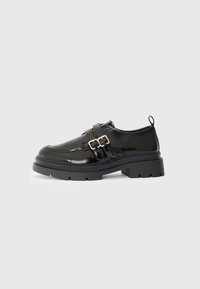 Black patent leather shoes with a chunky sole, featuring dual buckle straps, a rounded toe, and a pull tab on the heel.