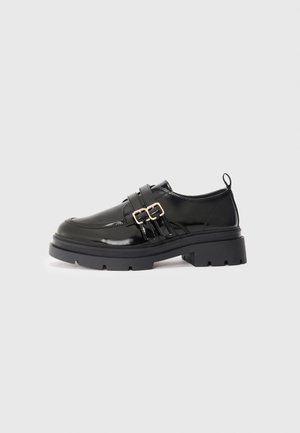Black patent leather shoes with a chunky sole, featuring dual buckle straps, a rounded toe, and a pull tab on the heel.