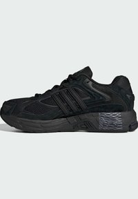 Black athletic shoe with mesh and suede upper, featuring three black stripes, textured midsole, and a patterned outsole design.