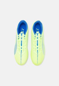 Zapatillas amarillas brillantes con acentos azules, material sintético suave y un diseño aerodinámico. Presentan cordones planos y cuellos acolchados.